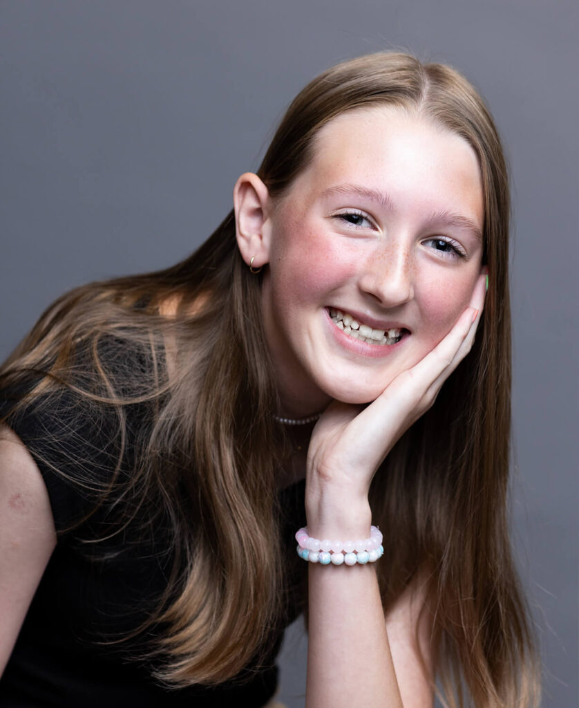 Smiling teen girl with long hair resting her chin on her hand