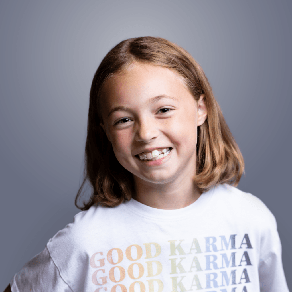 Smiling young girl wearing a Good Karma graphic t-shirt