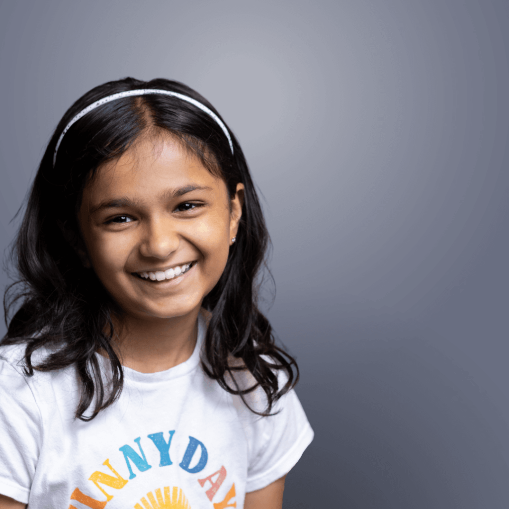 Smiling girl with a white headband wearing a Sunny Day t-shirt