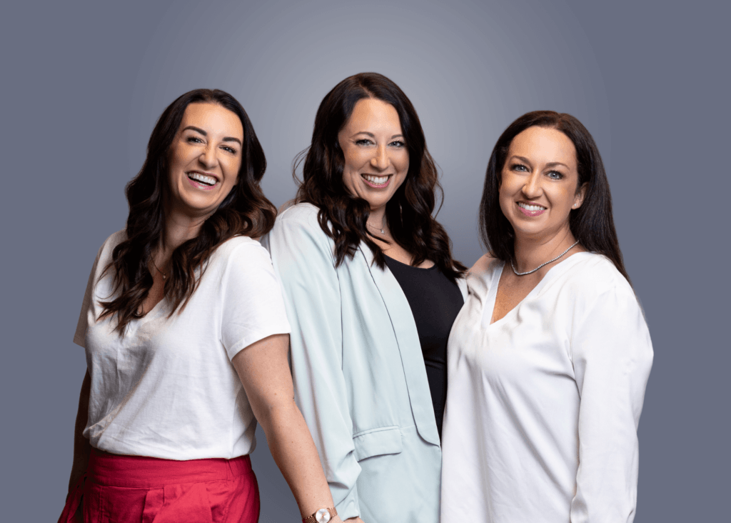 Three smiling team members in casual attire posing together