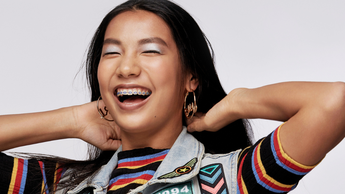 Young woman laughing with metal braces wearing colorful striped outfit