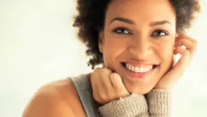 Smiling woman with curly hair resting her chin on her hand