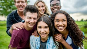 Group of smiling teens posing together outdoors in a grassy field