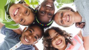 Group of smiling children huddled together in a circle viewed from below