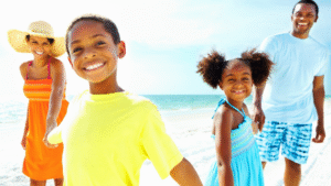 Smiling family of four in bright clothing walking together on a sunny beach