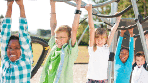 Group of smiling children playing on outdoor playground monkey bars