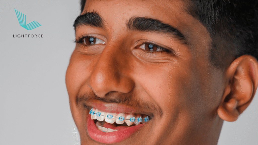 Smiling teen boy with blue and white braces beside a LightForce logo