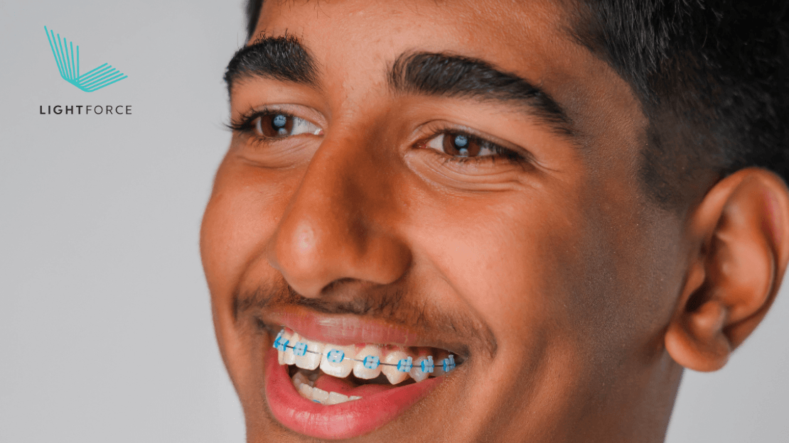Smiling teen boy with blue and white braces beside a LightForce logo