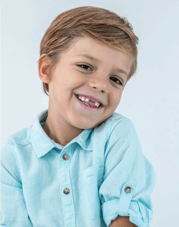 Smiling young boy with missing front tooth in a light blue button-up shirt