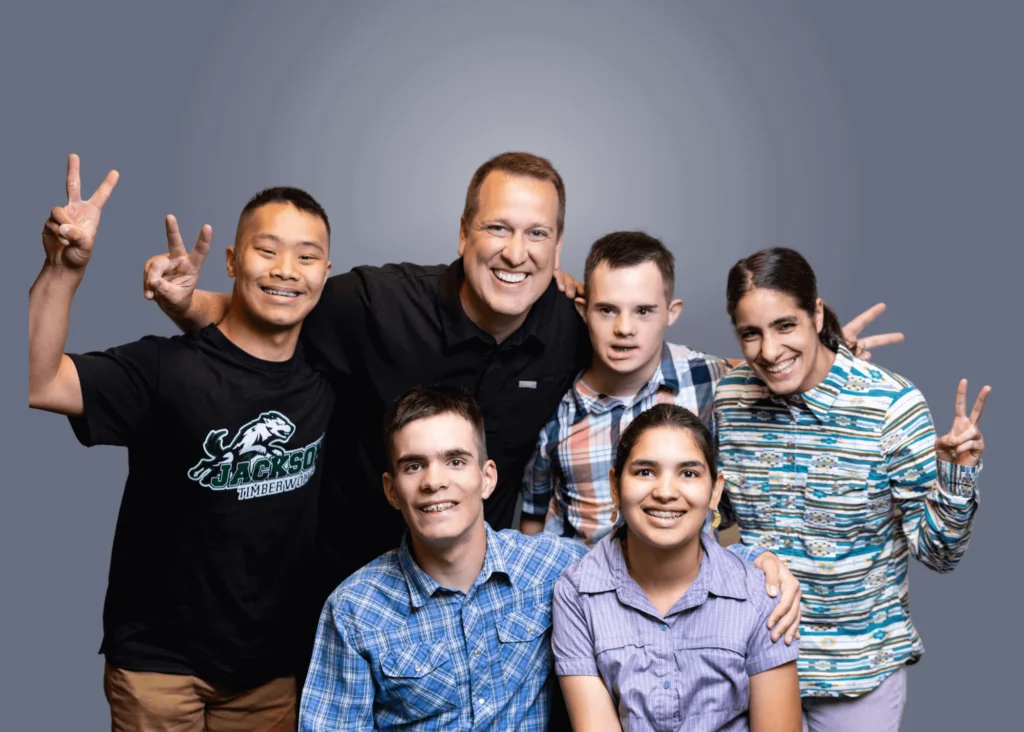 Group of teens and a smiling man giving peace signs in a studio photo